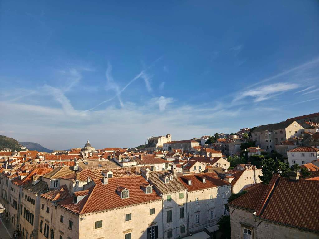 A scenic view of a historical town with red-tiled rooftops under a clear blue sky.