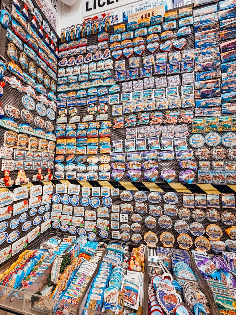 A display of various souvenirs including magnets and postcards, arranged on a wall with multiple sections showcasing different designs and themes related to travel and specific locations.