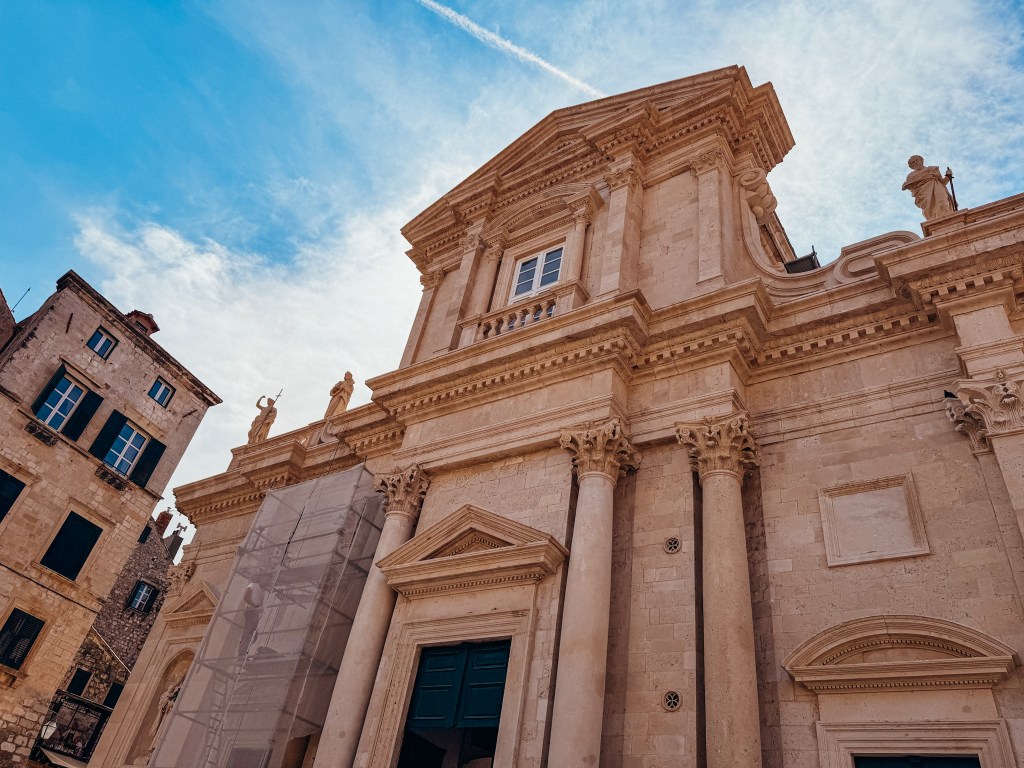 Close-up view of a historical building with ornate architecture, featuring columns and a decorative facade against a blue sky.
